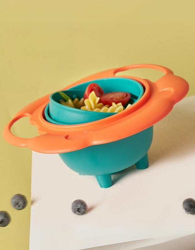 Colorful 360-degree rotating tumbler bowl filled with pasta and vegetables, designed for spill-free feeding.